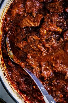 a pot full of chili with a spoon in it