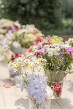 several vases filled with flowers sitting on top of a wooden table next to each other