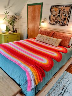 a bed with a colorful blanket on top of it in a bedroom next to two nightstands