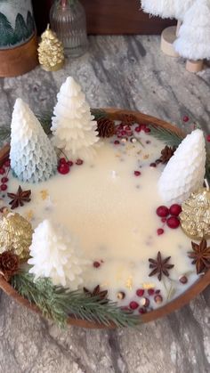 a bowl filled with white liquid surrounded by pine cones and other decorations on top of a table