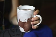 a person holding a coffee mug with chocolate on the outside and white paint on the inside