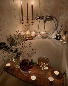 candles are lit in the bathroom next to a bathtub with flowers and fruit on it