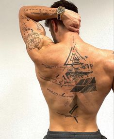 the back of a man with tattoos on his upper and lower half, holding his hand to his head