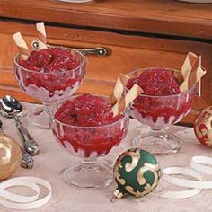 three glasses filled with raspberry souffle sitting on a table next to christmas ornaments