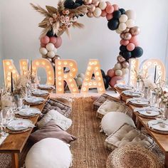 a table set up for a party with balloons and lights in the shape of letters