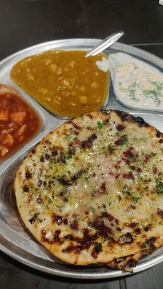 a silver plate topped with different types of food on top of a metal tray covered in sauces and condiments