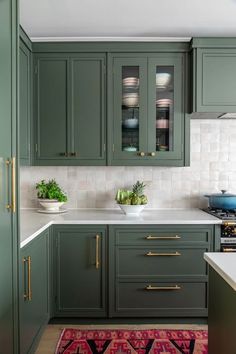 a kitchen with green cabinets and gold pulls on the cupboards is pictured in this image