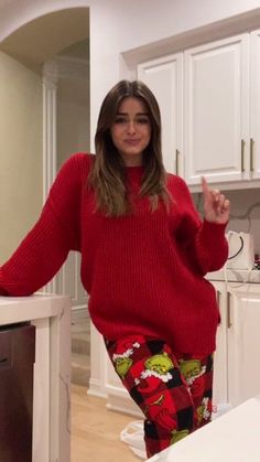 a woman standing in a kitchen with her arms out and pointing at the camera while wearing pajamas