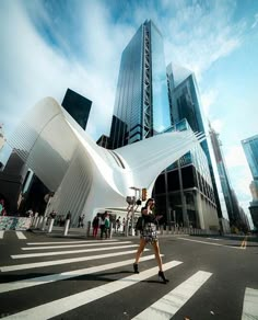 a woman walking across a street in front of tall buildings