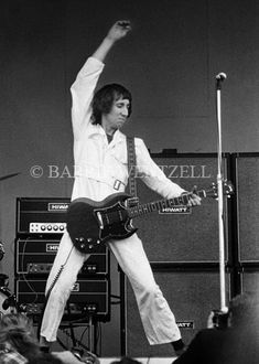 the man is playing guitar on stage with his arms in the air and one hand up