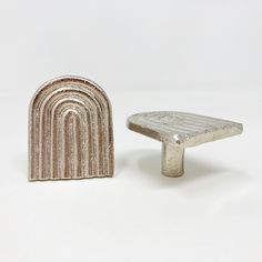 two silver objects sitting next to each other on a white surface