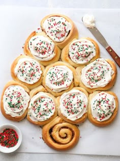 a white cutting board topped with cookies covered in frosting and sprinkles