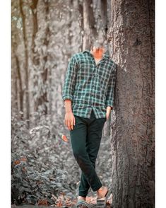 a man standing next to a tree in the woods