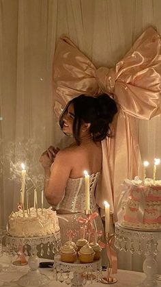 a woman standing in front of a table with cupcakes and candles on it