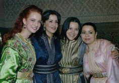 four women are posing for the camera in their ethnic garb and dress clothes, with one woman holding her arm around the other's shoulder