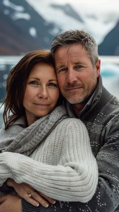 a man and woman hugging each other in front of snow covered mountains with icebergs behind them