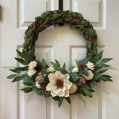 a wreath on the front door with flowers and greenery hanging from it's side