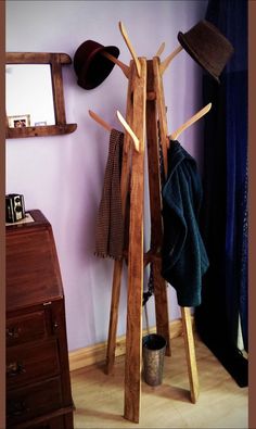 a coat rack with hats and scarves on it in front of a purple wall