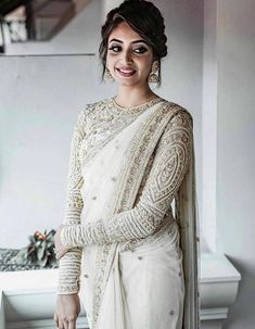 a woman in a white sari and matching jewelry poses for the camera with her hands on her hips