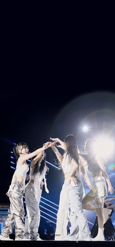 the group of young women are dancing on stage at an event with their hands in each other's pockets