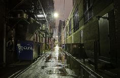 an alleyway in the city at night with rain on the ground and street lights