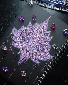 an intricately designed notebook with jewels on the cover and in front of it is a purple flower