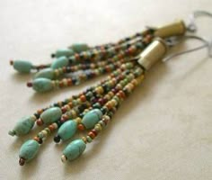 a pair of earrings with beads and metal hooks on a white tablecloth covered surface