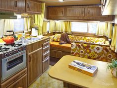 a kitchen and living room in a trailer or camper with yellow curtains on the windows