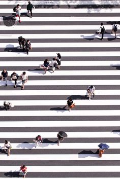 an overhead view of people walking across a crosswalk with umbrellas over their heads