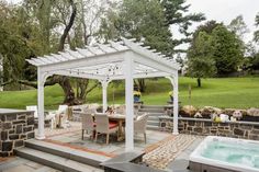 a hot tub sitting next to a stone wall and covered patio with an outdoor jacuzzi