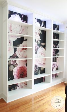 a white bookcase with flowers painted on the front and back sides, along with wooden flooring