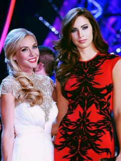 two beautiful women standing next to each other on a catwalk at a fashion show