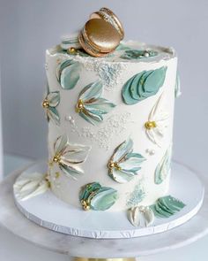 a wedding cake decorated with gold and green leaves