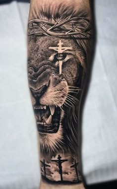 a man's arm with a lion and cross tattoo on it, in black and grey