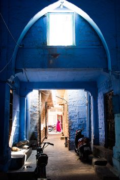 an alley way with blue walls and motorcycles parked on the side walk in front of it