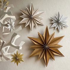 three paper stars are hanging on the wall next to each other, one is gold and white