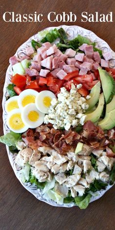 a salad with hard boiled eggs, ham, lettuce and tomatoes on it