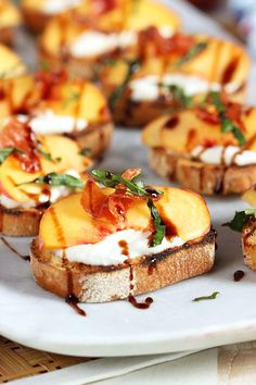 toasted bread topped with peaches, cream and herbs on a white platter