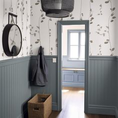 a hallway with blue painted walls and wood flooring is pictured in this image, there are two baskets on the wall next to the door