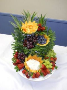 a plate topped with fruit and flowers on top of a white tablecloth covered table