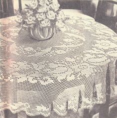 an old photo of a table with flowers in a vase on top of it and lace doily around the table