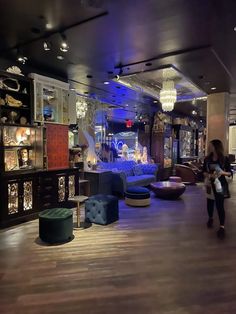 a woman is walking through a large room with furniture and chandeliers on the walls