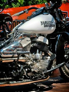 a harley davidson motorcycle parked in front of an orange wall with trees and bushes behind it