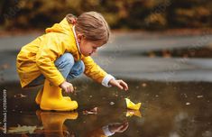 a little boy playing in the rain with yellow rubber boots stock photo and royalty free images