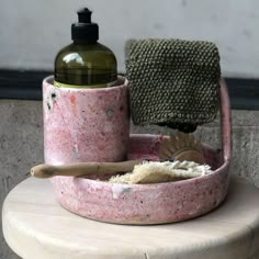 a soap dish with a scrubber and rag on it sitting on a stool next to a bottle