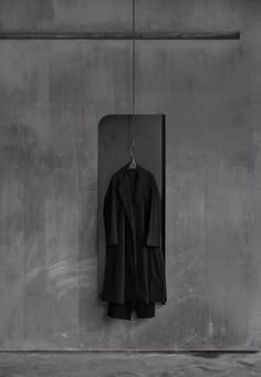 a black coat hanging on a gray wall