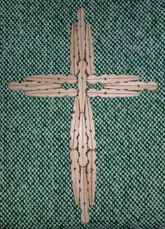 a cross made out of wooden sticks sitting on top of a green and white checkered cloth