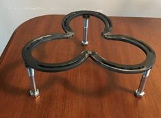 a wooden table topped with two metal heart shaped brackets on top of each other,