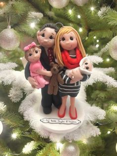 a christmas ornament with a family holding a baby in front of a tree