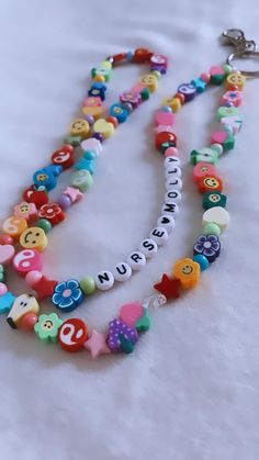 a multicolored beaded necklace with letters and numbers is displayed on a white surface